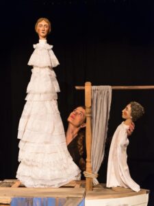 Frau mit zwei Theaterpuppen, schwarzer Hintergrund